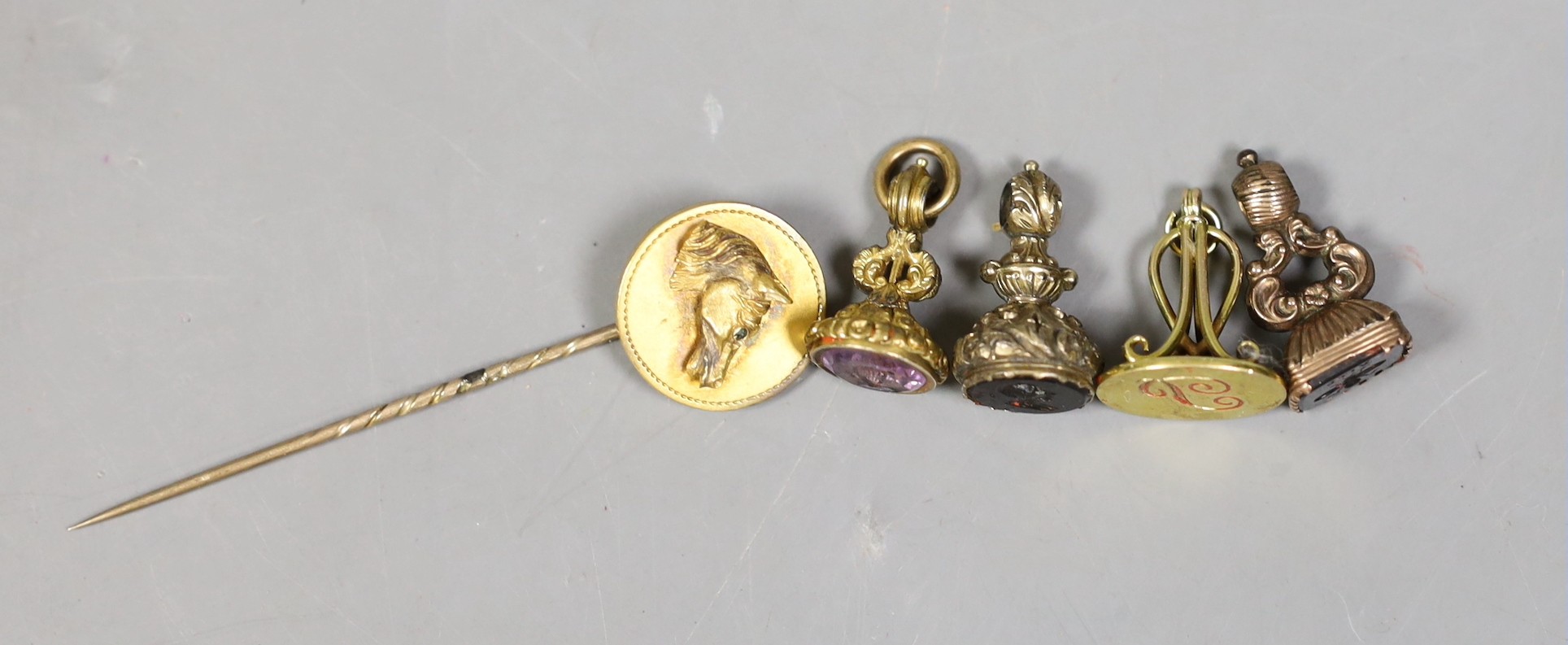 Three Victorian gilt metal fob seals, two set with bloodstone and carved with bust or bee, the other set with amethyst, a similar 9ct fob seal, a yellow metal horse head stick pin and a group of envelopes with wax seals.